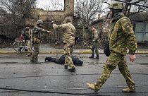 Militares ucraniano junto a un cuerpo tendido en el suelo en Bucha, Ucrania