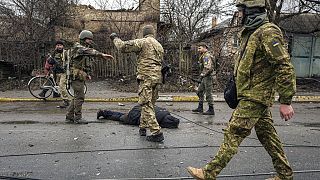 Militares ucraniano junto a un cuerpo tendido en el suelo en Bucha, Ucrania