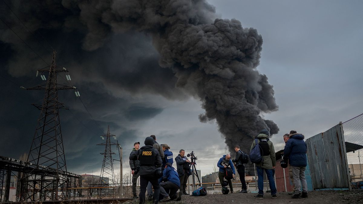 Journalists and residents stand as smoke rises after an attack by Russian army in Odessa, on April 3, 2022.