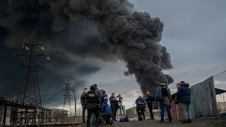 Journalists and residents stand as smoke rises after an attack by Russian army in Odessa, on April 3, 2022.