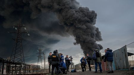 Journalists and residents stand as smoke rises after an attack by Russian army in Odessa, on April 3, 2022.