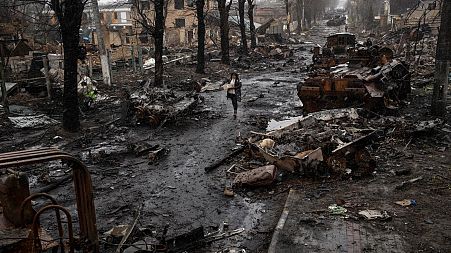 A woman walks amid destroyed Russian tanks in Bucha, in the outskirts of Kyiv, Ukraine, Sunday, April 3, 2022.