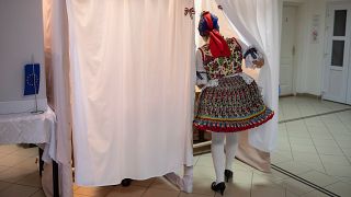 Женщина в национальной одежде заходит в кабинку для голосования в городе Буяк, Венгрия.