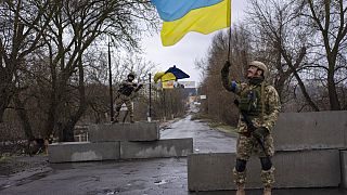 Ουκρανοί στρατιώτες ανεμίζουν τη σημαία της χώρας τους σε σημείο ελέγχου στην απελευθερωμένη Μπούτσα στα περίχωρα του Κιέβου