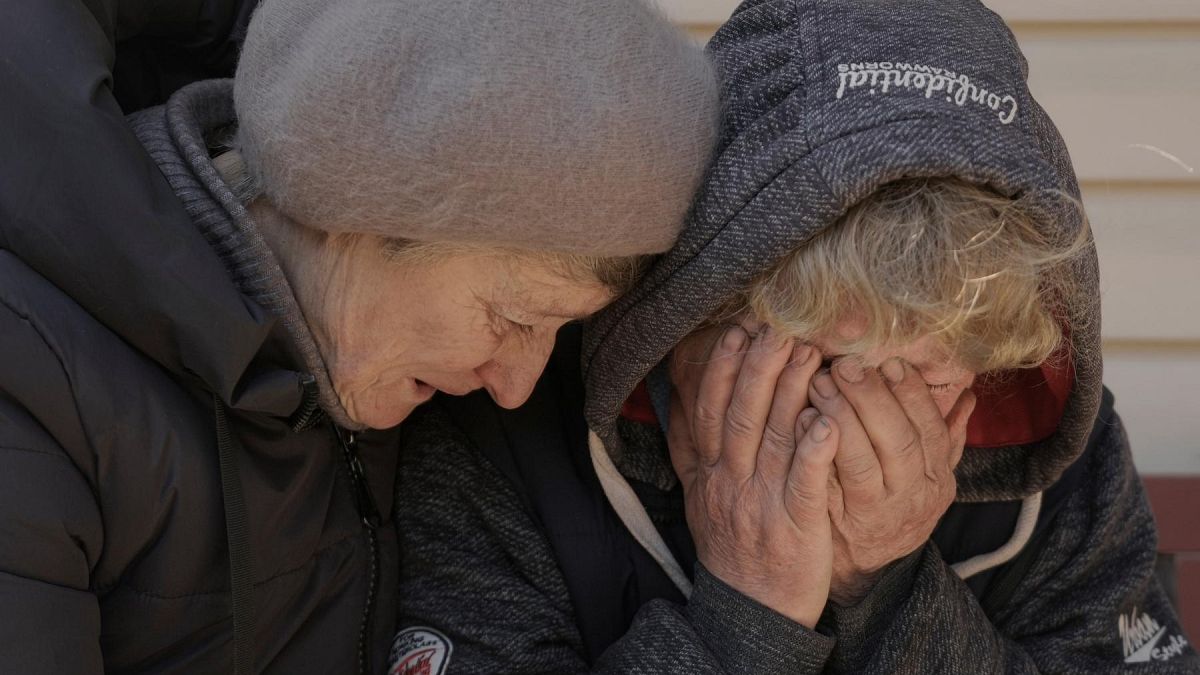 A neighbor comforts Natalya, whose husband and nephew were killed by Russian forces, as she cries in her garden in Bucha, Ukraine, Monday, April 4, 2022.