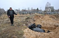 Un homme près d'une fosse commune à Boutcha (Ukraine), le 3 avril 2022
