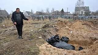 Un homme près d'une fosse commune à Boutcha (Ukraine), le 3 avril 2022