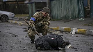 Un soldado ucraniano examina un cadáver en una calle de Bucha.