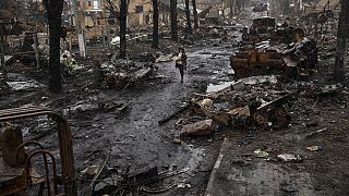 A woman walks amid destroyed Russian tanks in Bucha, in the outskirts of Kyiv, Ukraine, Sunday, April 3, 2022.