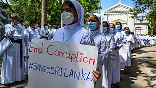Katholische Priester und Nonnen halten Plakate bei einer Demo gegen die Wirtschaftskrise in Colombo.