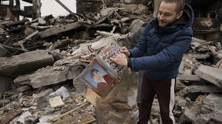 Ein Mann zieht ein altes Schulheft mit Klassenfotos aus dem Schutt seines zerstörten Hauses in Borodjanka nahe Kiew.