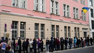 Ukrainian nationals wait outside the consular department of the Ukrainian embassy in Berlin.