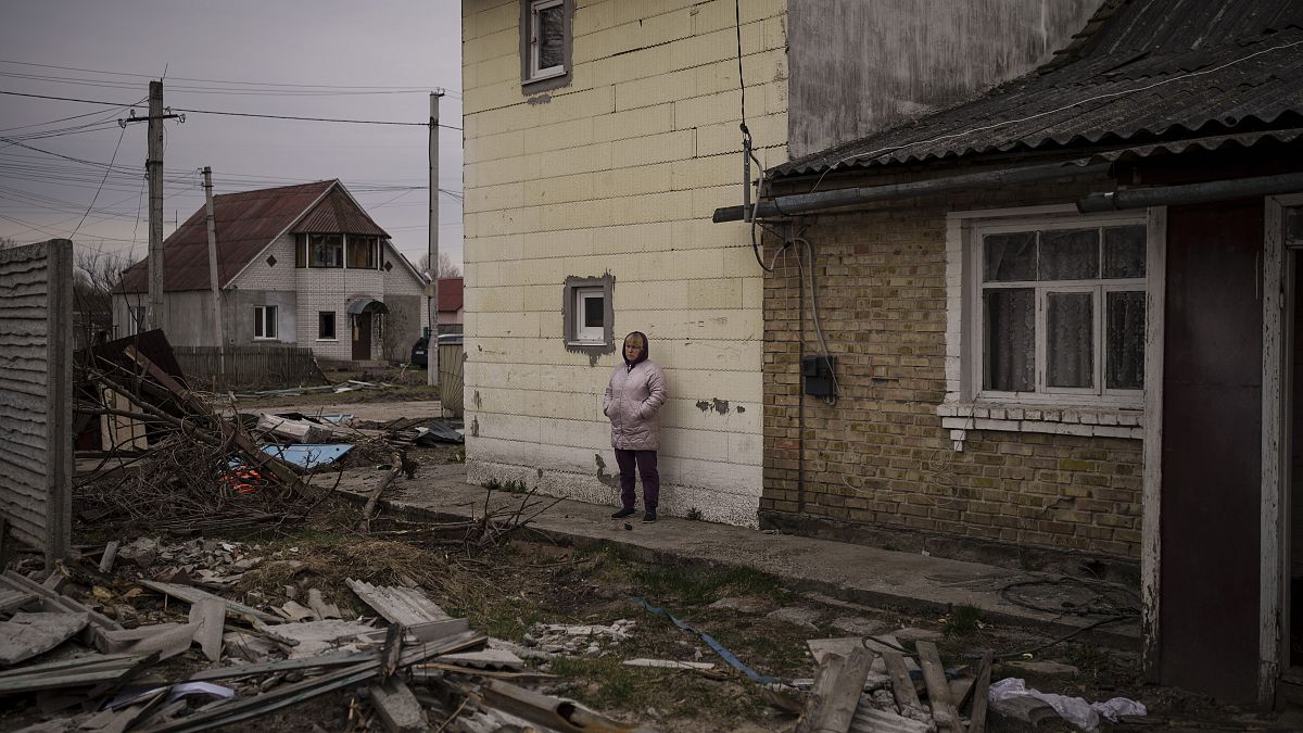 امرأة أوكرانية أمام بيت مدمر في بوتشا 