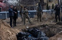 Katonák és civilek a bucsában talált tömegsír mellett 2022. április 4-én