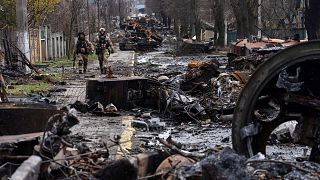Des soldats ukrainiens marchent au milieu de chars russes détruits à Boutcha