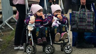 A woman with two children wait in a line after fleeing the war from neighbouring Ukraine, at the border crossing in Medyka, southeastern Poland, Wednesday, April 6, 2022.