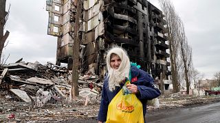 An elderly woman walks by an apartment building destroyed in the Russian shelling in Borodyanka, Ukraine, Wednesday, April 6, 2022