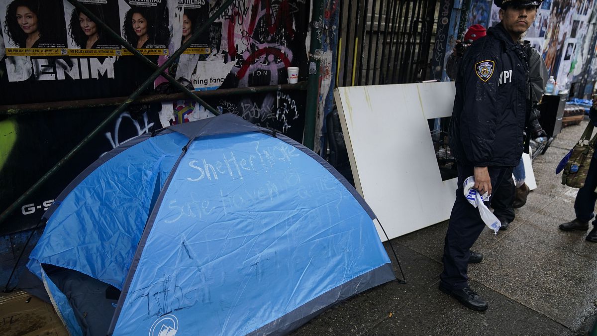 ضابط شرطة يقف بجوار خيمة في مخيم صغير للمشردين في نيويورك، الأربعاء 6 أبريل 2022