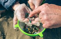 People investigating small pieces of plastic found on a beach.