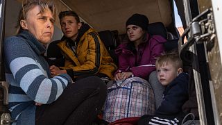 From left to right, Oksana Gavrielutca 41, sits at the back of a bus with her children Oleg 18, Diana 17 and Vlad 5 after they flee from Snigiriovka village, in Mikolaiv distr