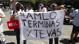 Manifestantes opuestos a López Obrador con una pancarta que dice: AMLO, terminas y te vas
