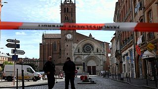 Security personnel gather at the entrance of Saint Etienne Cathedral in Toulouse.