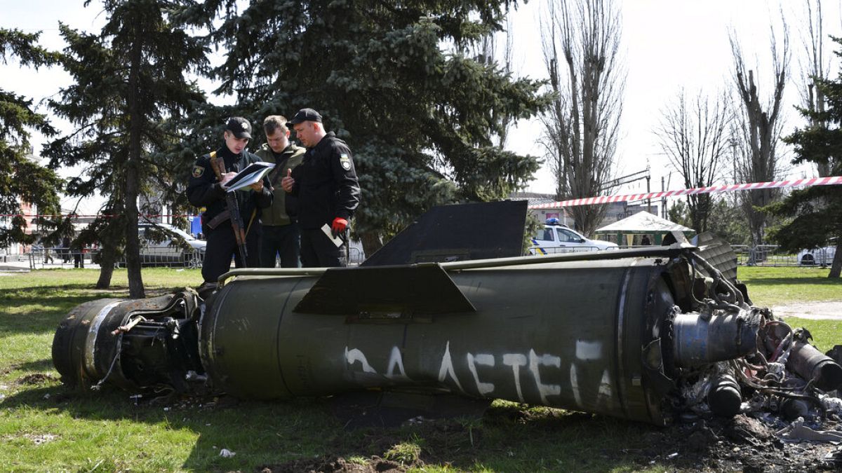 Украинские военные рядом с фрагментом ракеты "Точка-У" с надписью на русском языке "За детей" после обстрела вокзала в Краматорске