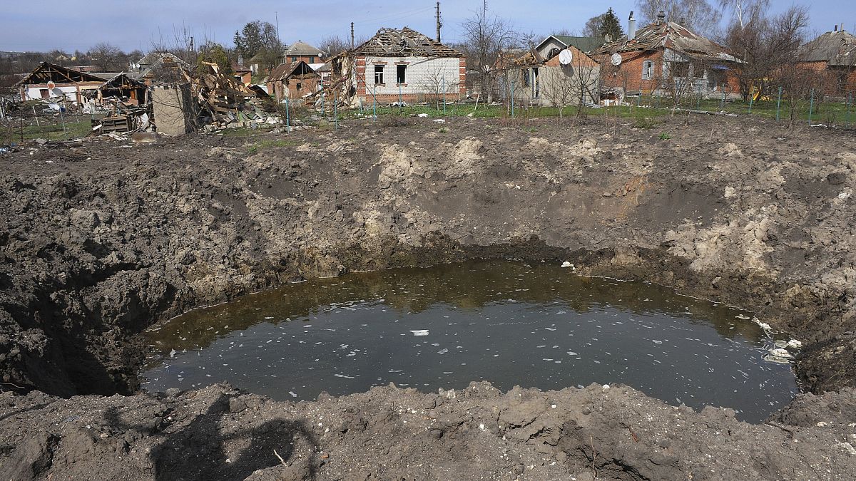 Robbanástól keletkezett kráter orosz tüzérségi támadásokban megrongált házak közelében a Harkiv közelében lévő Csuhuivban 2022. április 8-án