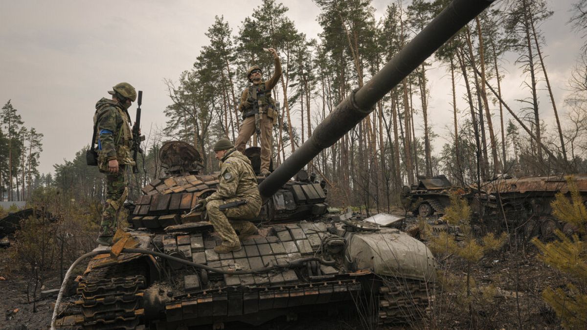 Ukrainian serviceman takes a selfie standing on a destroyed Russian tank