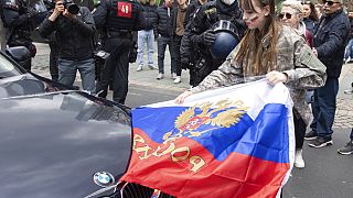 Участница автопробега в поддержку РФ снимает российский флаг по просьбе полицейских, Франкфурт, Германия, 10 апреля 2022 г.