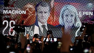 A screen shows French President Emmanuel Macron and centrist candidate for reelection and far-right candidate Marine Le Pen at her election day headquarters, in Paris.