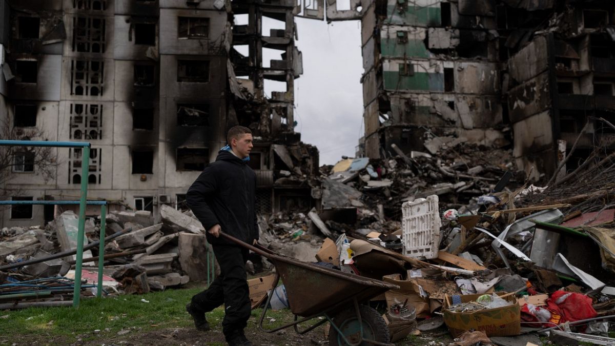 Ein junger Mann schiebt eine Schubkarre vor einem zerstörten Wohnhaus in der Stadt Borodjanka (10. April 2022). 