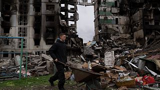 Ein junger Mann schiebt eine Schubkarre vor einem zerstörten Wohnhaus in der Stadt Borodjanka (10. April 2022).