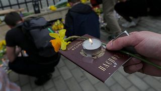 A demonstrator holds a Russian passport with a candle and a flower during an anti-war action in front of Ukrainian Embassy in Tbilisi, Georgia.