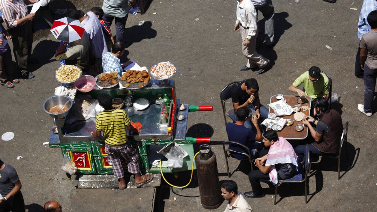  بائع متجول مصري يقف بجانب عربته يقدم وجبة الفول التقليدية في أحد شوارع القاهرة، مصر، الجمعة 20 أبريل 2012