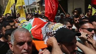 El jóven palestino de 21 años Mohamed Ghnaim, siendo transportado por las calles por cientos de dolientes, 11/4/2022