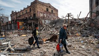 Residents carry their belongings near buildings destroyed in the course of Russia's war against Ukraine, in the southern port city of Mariupol, Ukraine. April 10, 2022.