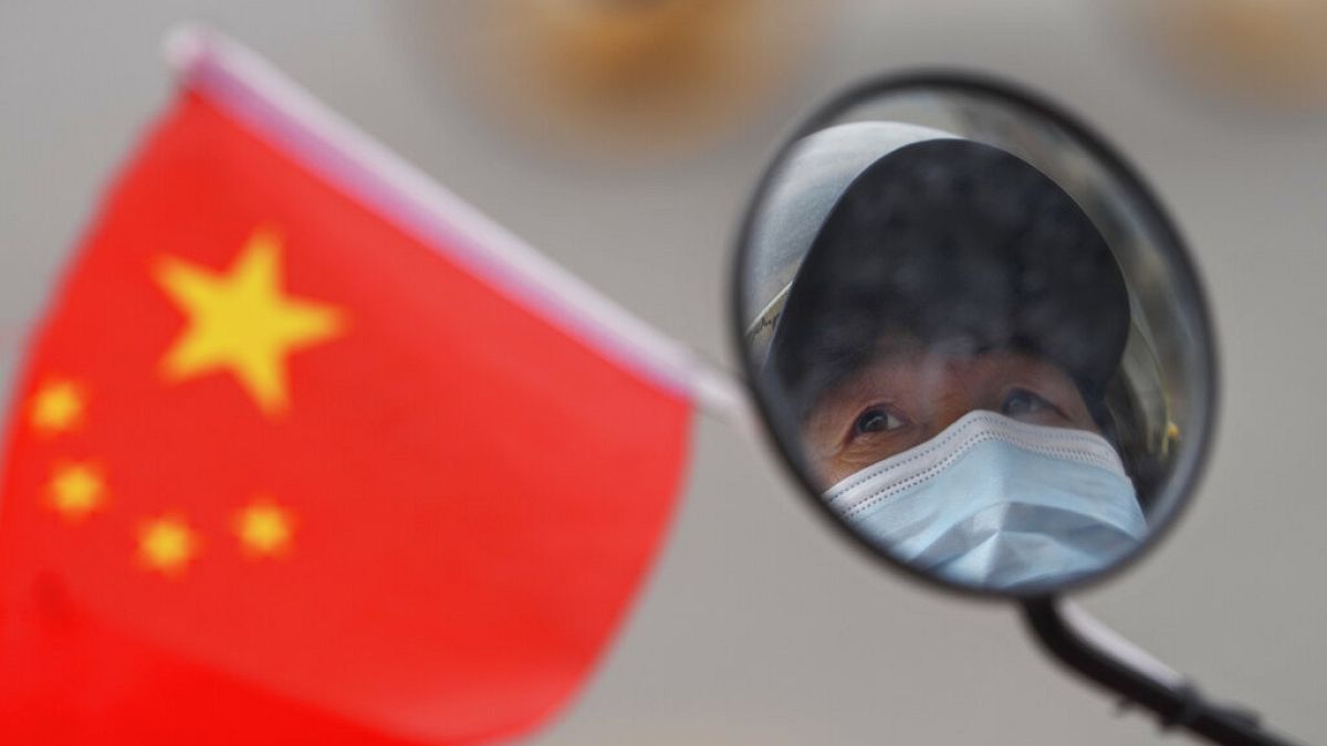 Una mujer lleva una mascarilla protectora mientras conduce su vehículo en Pekín