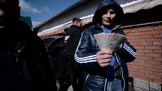 A man holds a handful of Ukranian Hryvnia money