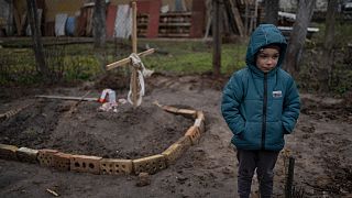 In the courtyard of their house, Vlad, 6, stands near the grave of his mother, who died, on the outskirts of Kyiv, Ukraine, Monday, April 4, 2022