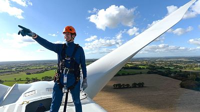 An engineer standing on a wind turbine in France.