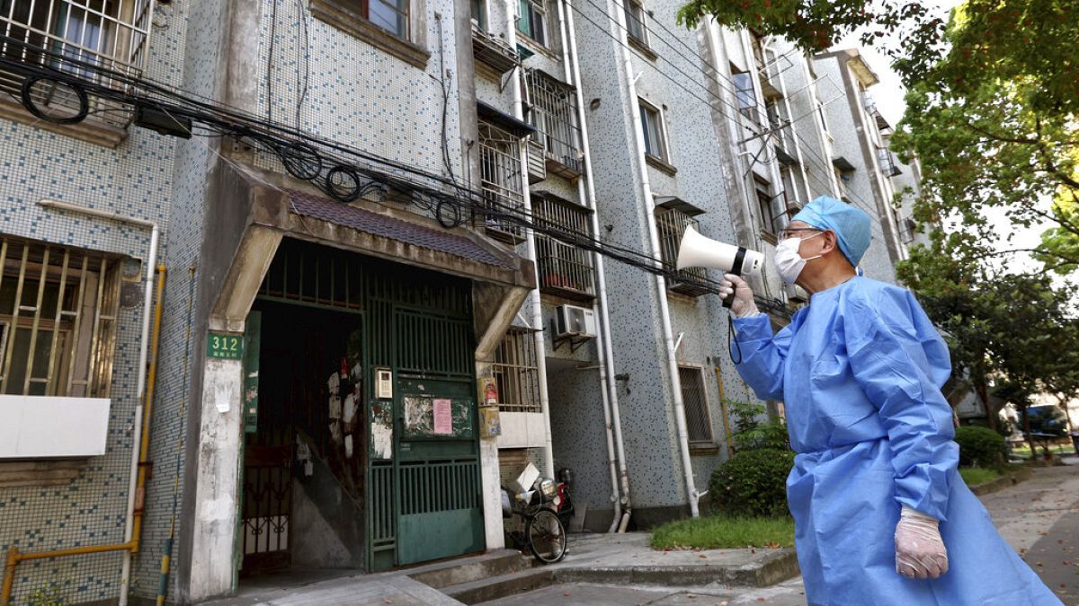 Un volontaire utilise un mégaphone pour parler à des habitants d'un immeuble de Shanghai, le 12 avril 2022