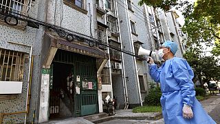 Un volontaire utilise un mégaphone pour parler à des habitants d'un immeuble de Shanghai, le 12 avril 2022