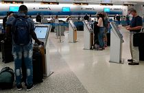 Travelers use the self-service kiosk to check in and pay for luggage at the American Airlines terminal, in Miami.