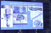 Photos of fragments of a bomb are displayed above officials in Zagreb.