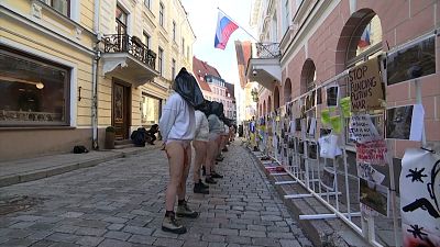 Line of women with their heads in bin bags in front of Tallinn's Russian embassy.