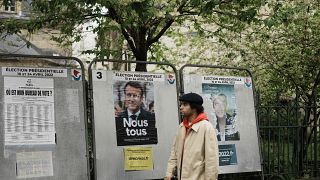Un hombre pasa junto a los carteles rotos de la campaña presidencial de Emmanuel Macron y Marine Le Pen
