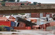 Residents of Umlazi township stand over a bridge and watch containers that fell over at a container storage facility following heavy rains and winds in Durban.
