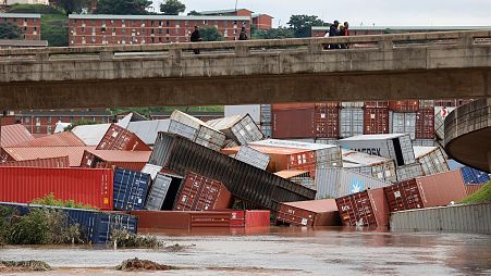 Residents of Umlazi township stand over a bridge and watch containers that fell over at a container storage facility following heavy rains and winds in Durban.