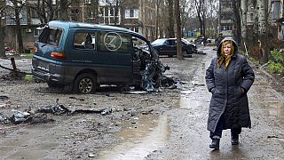 Beschädigter Wagen mit Z - und eine Frau in Mairupol